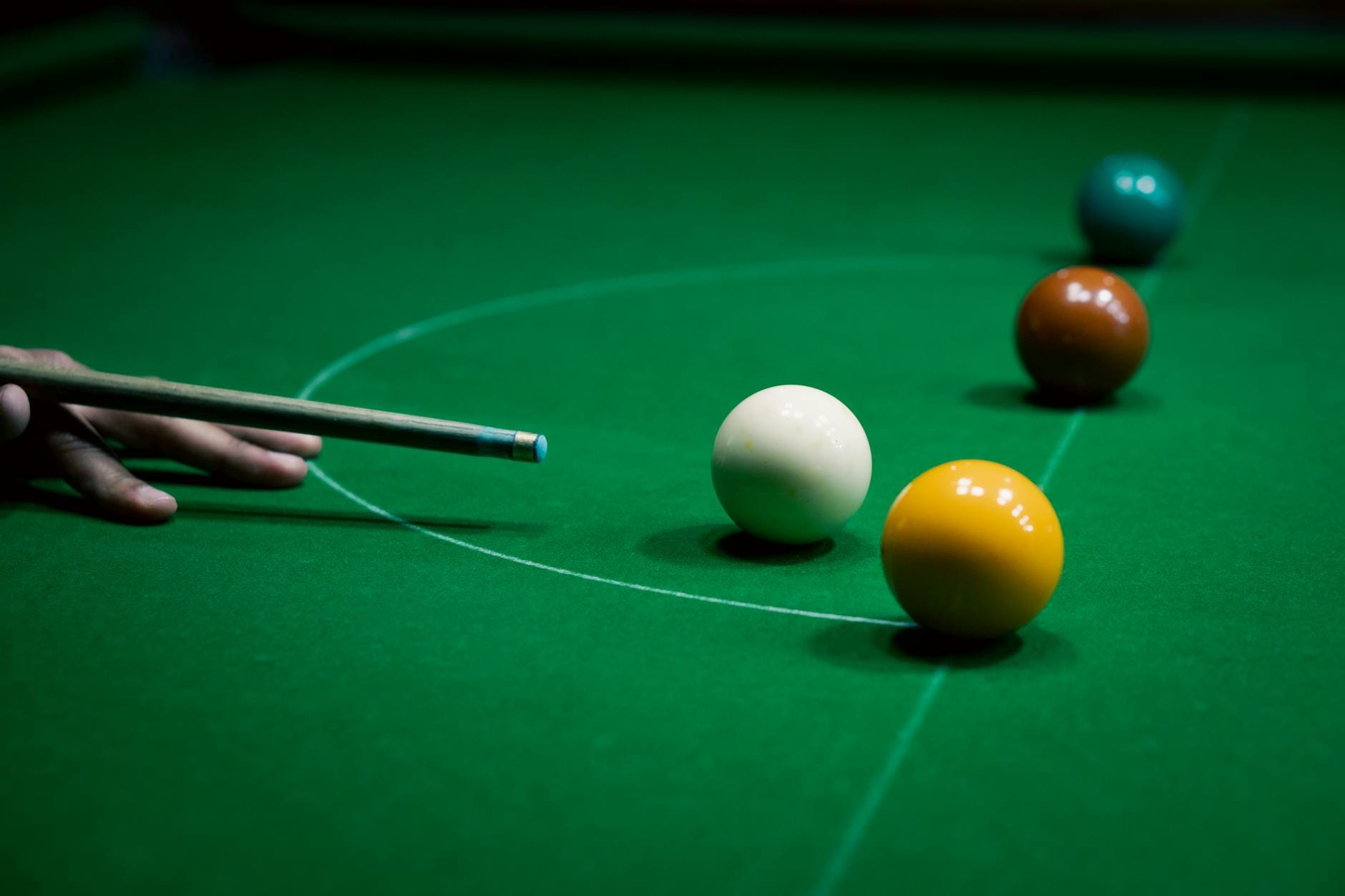 Kij snookerowy celujący w kolorowe bile na zielonym stole