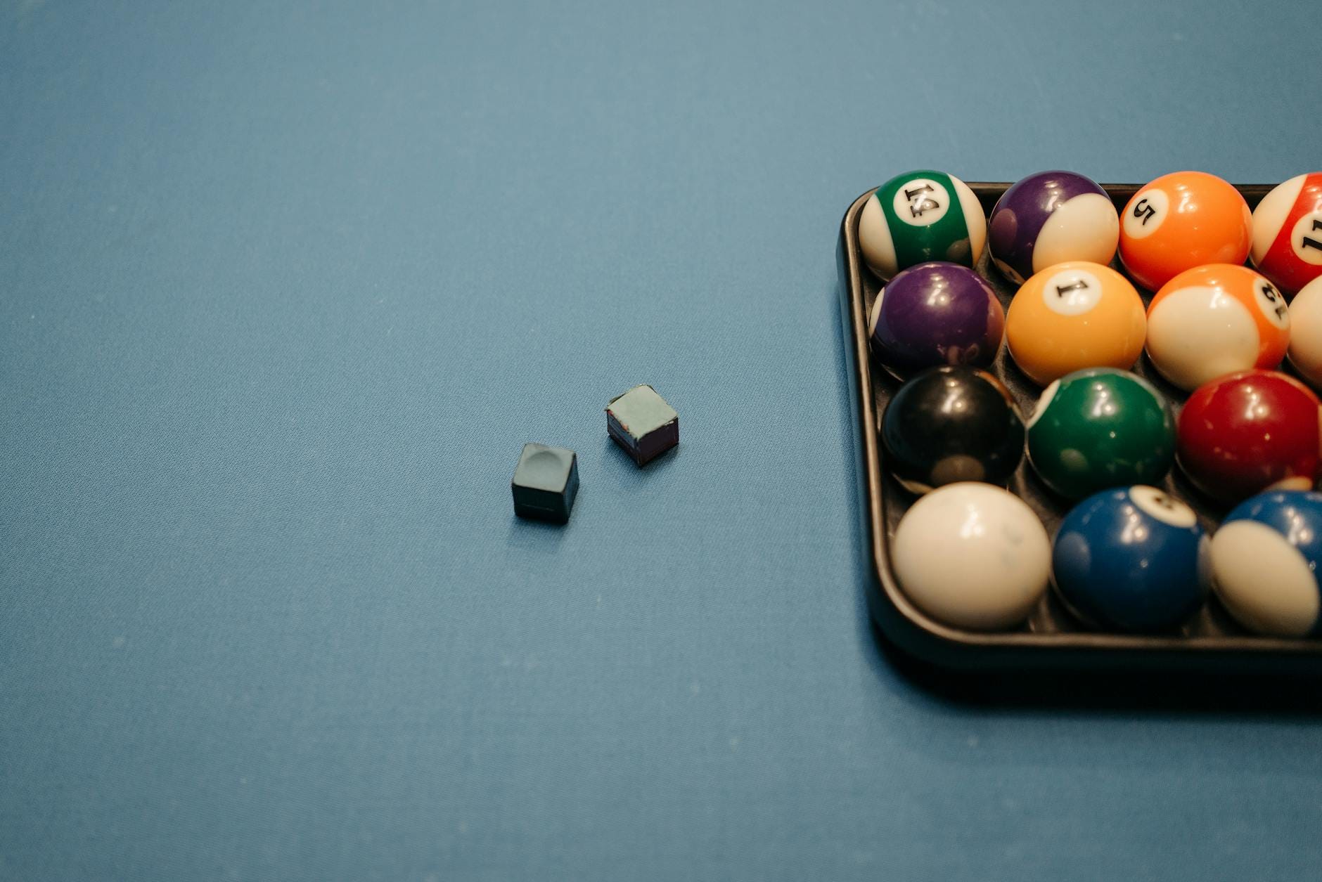 Kolorowe bile bilardowe i kostki kredy na niebieskim suknie