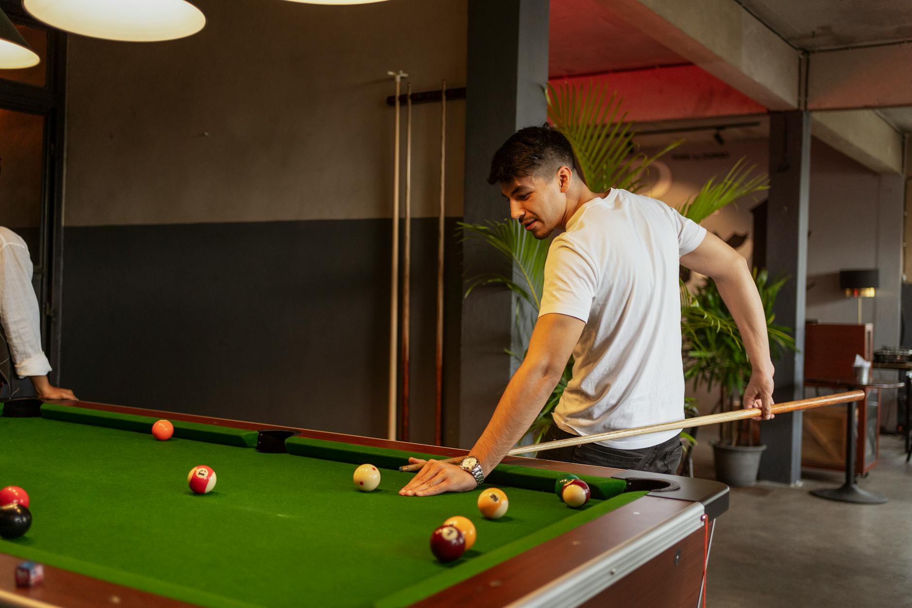 Trening na cienkie cięcia: jak nie „odstawić” białej bili po zagraniu Mężczyzna koncentrujący się nad uderzeniem w bilard w eleganckim klubie