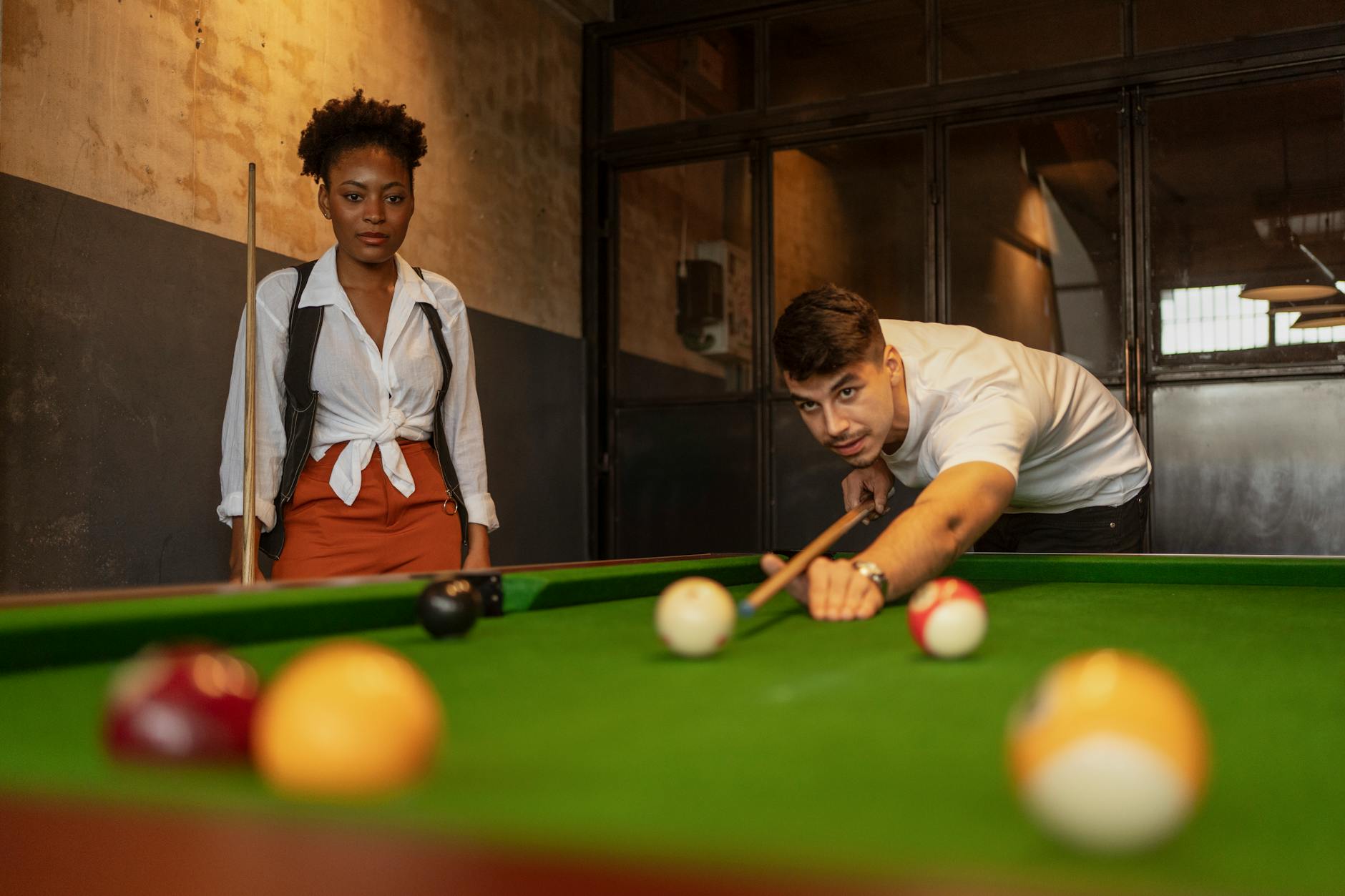 Dwoje młodych dorosłych gra w bilard w stylowym, retro klubie
