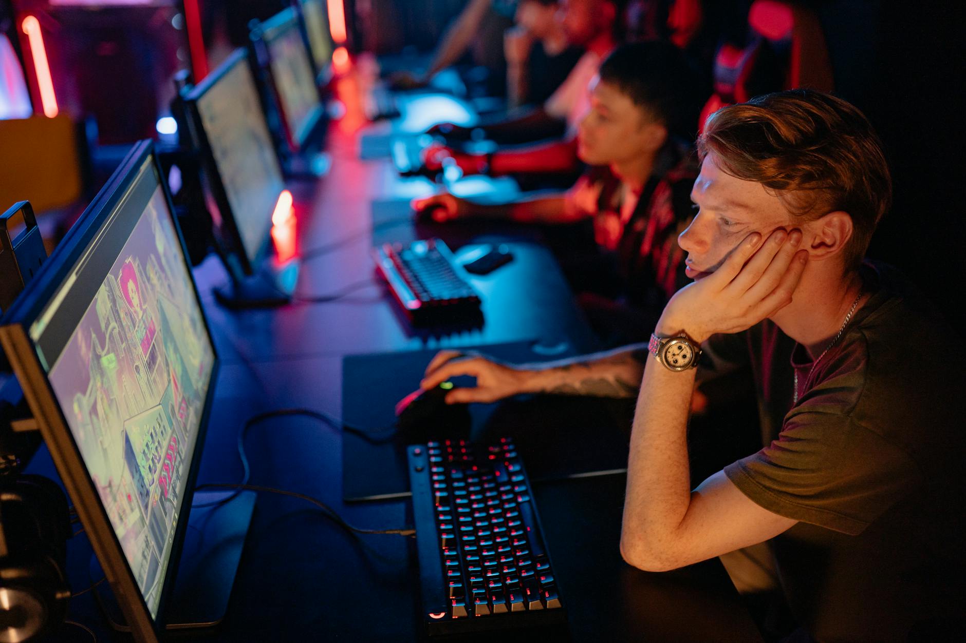 Gracze esports przy komputerach podczas turnieju w słabo oświetlonej hali