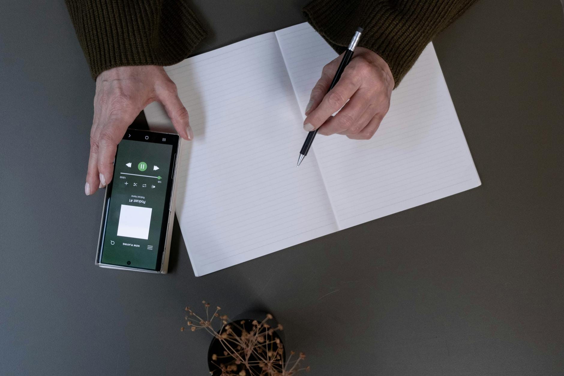 Osoba robiąca notatki z meczu przy telefonie leżącym na biurku