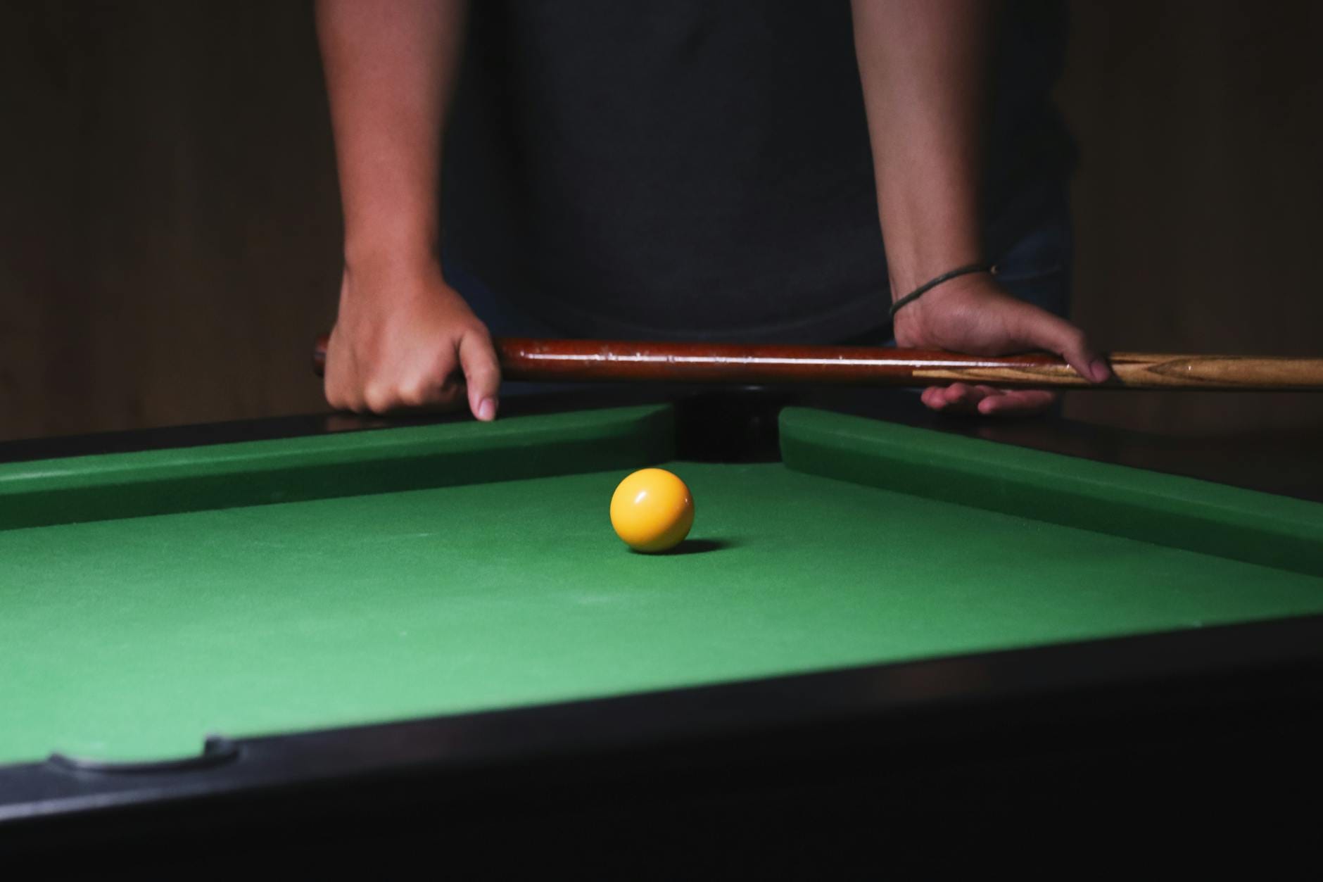 Zawodnik celuje kijem bilardowym w żółtą bilę na zielonym stole