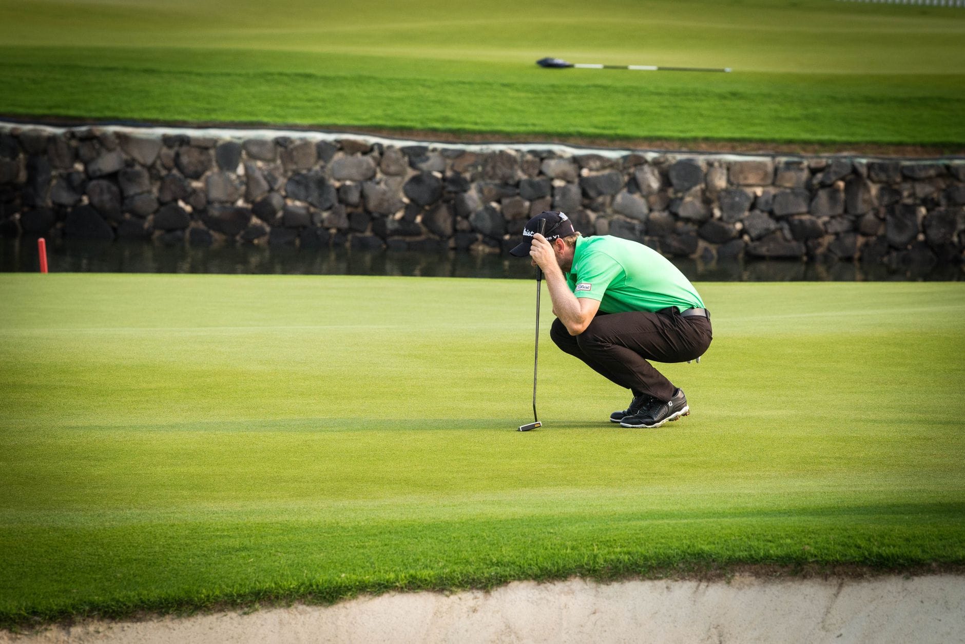 Golfista w kuckach planujący putt na zielonym greenie podczas turnieju